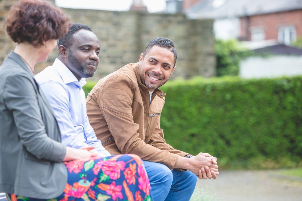 Baptist training image: three people talking on bench outside

