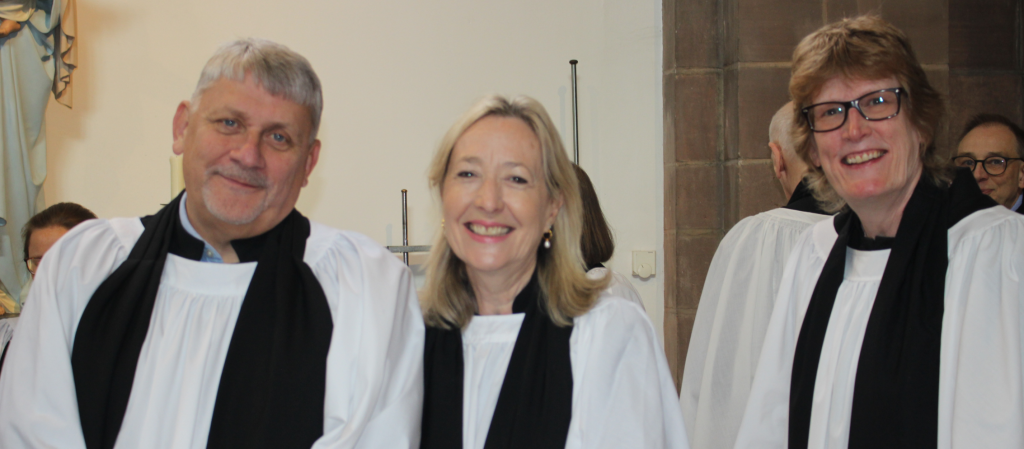 Three ordinands wearing vicars' vestments