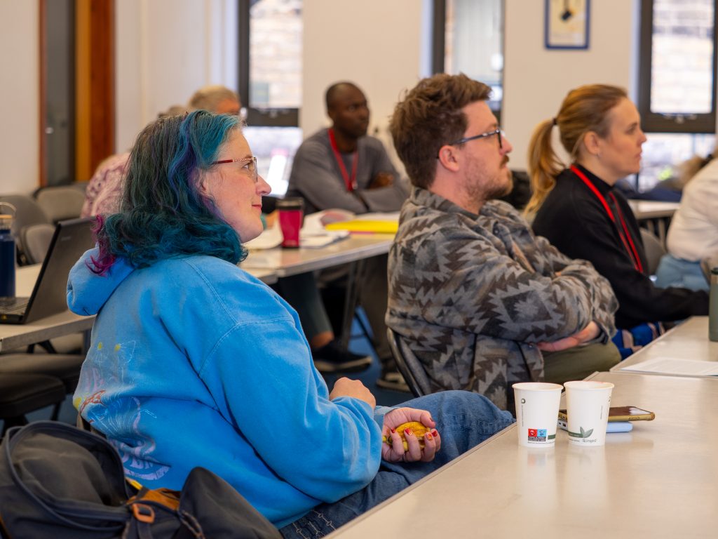 People in a classroom sitting listening to a teacher