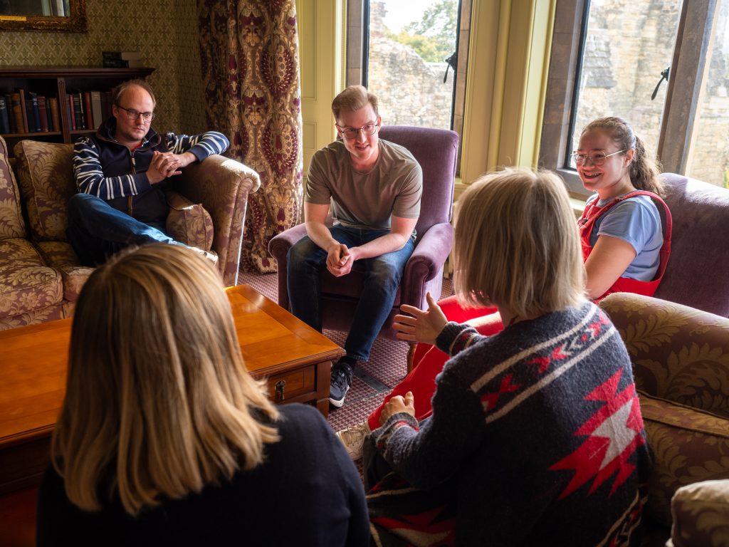 People sitting in a circle in a room with a bay window