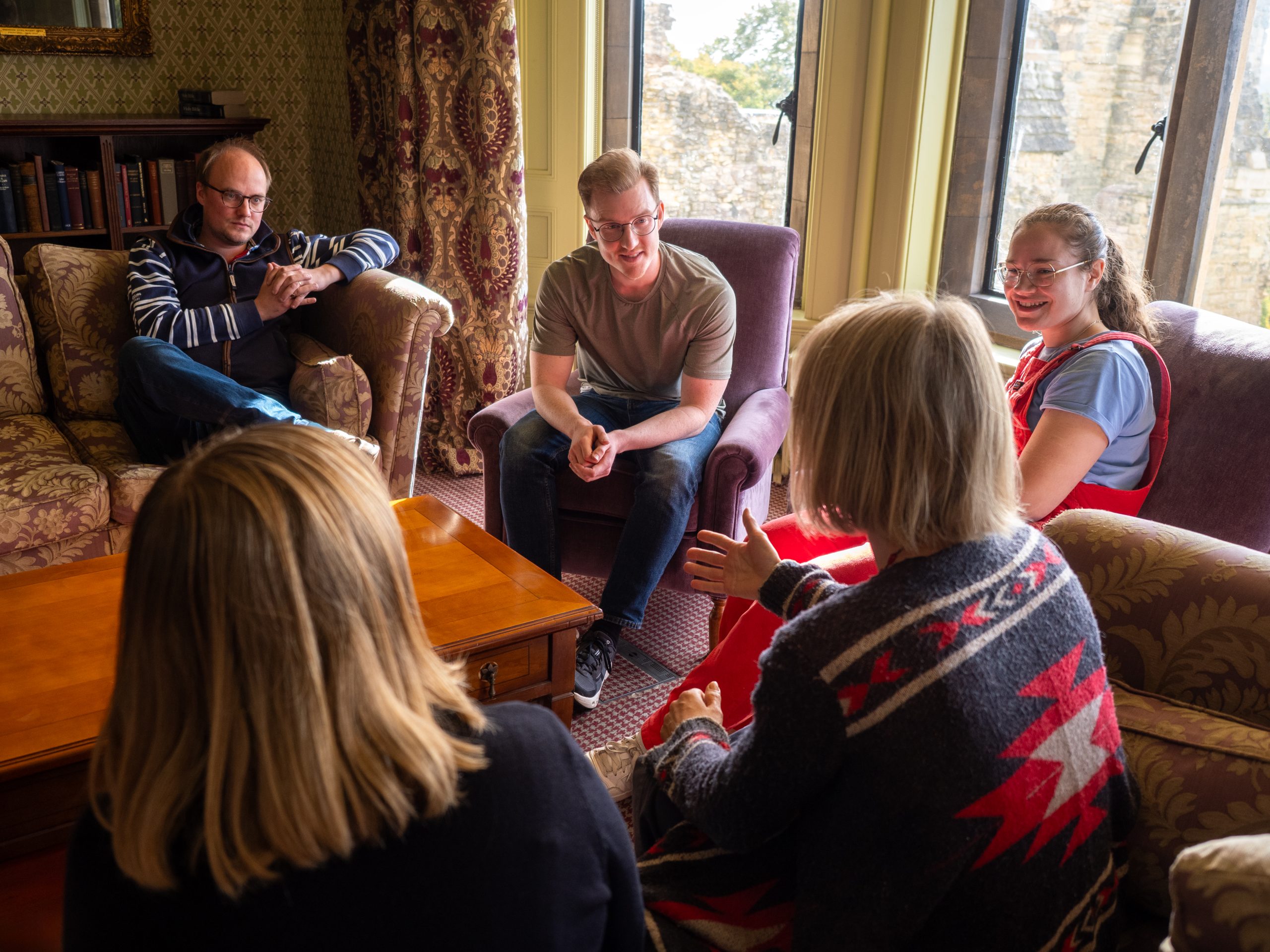 People sitting in a circle in a room with a bay window