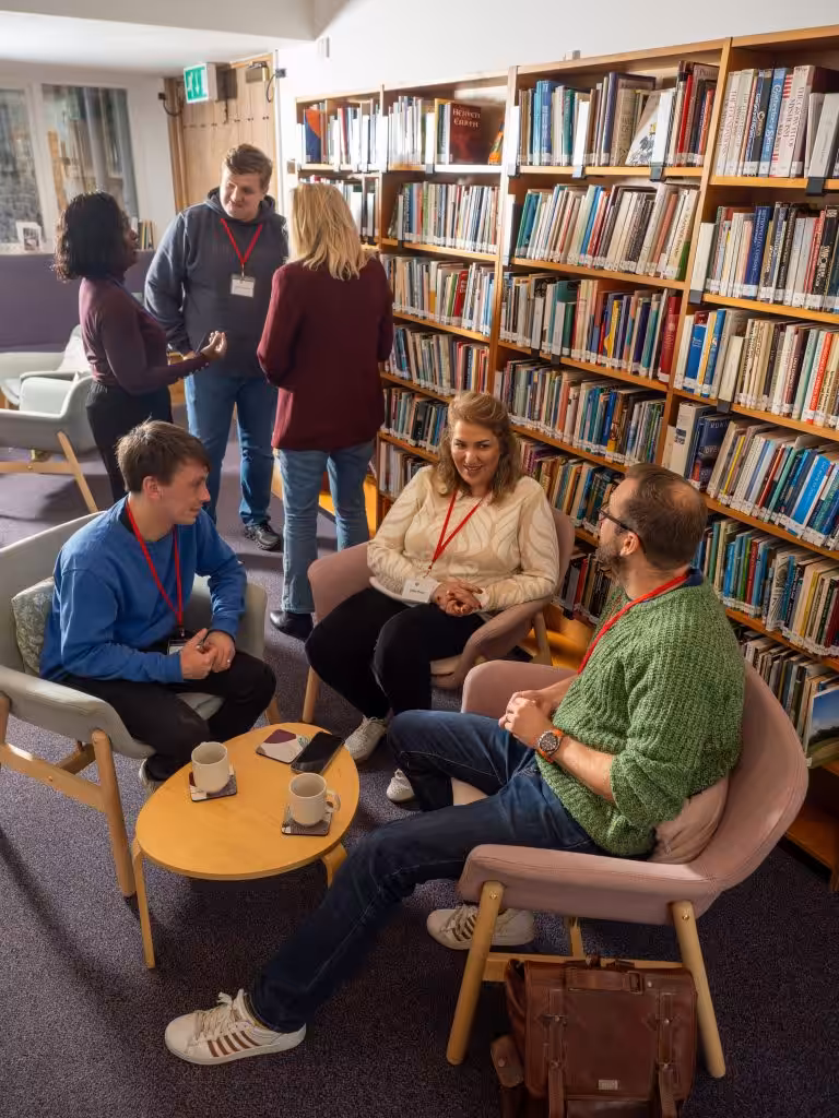 People sitting in comfortable chairs in a library, discussing things