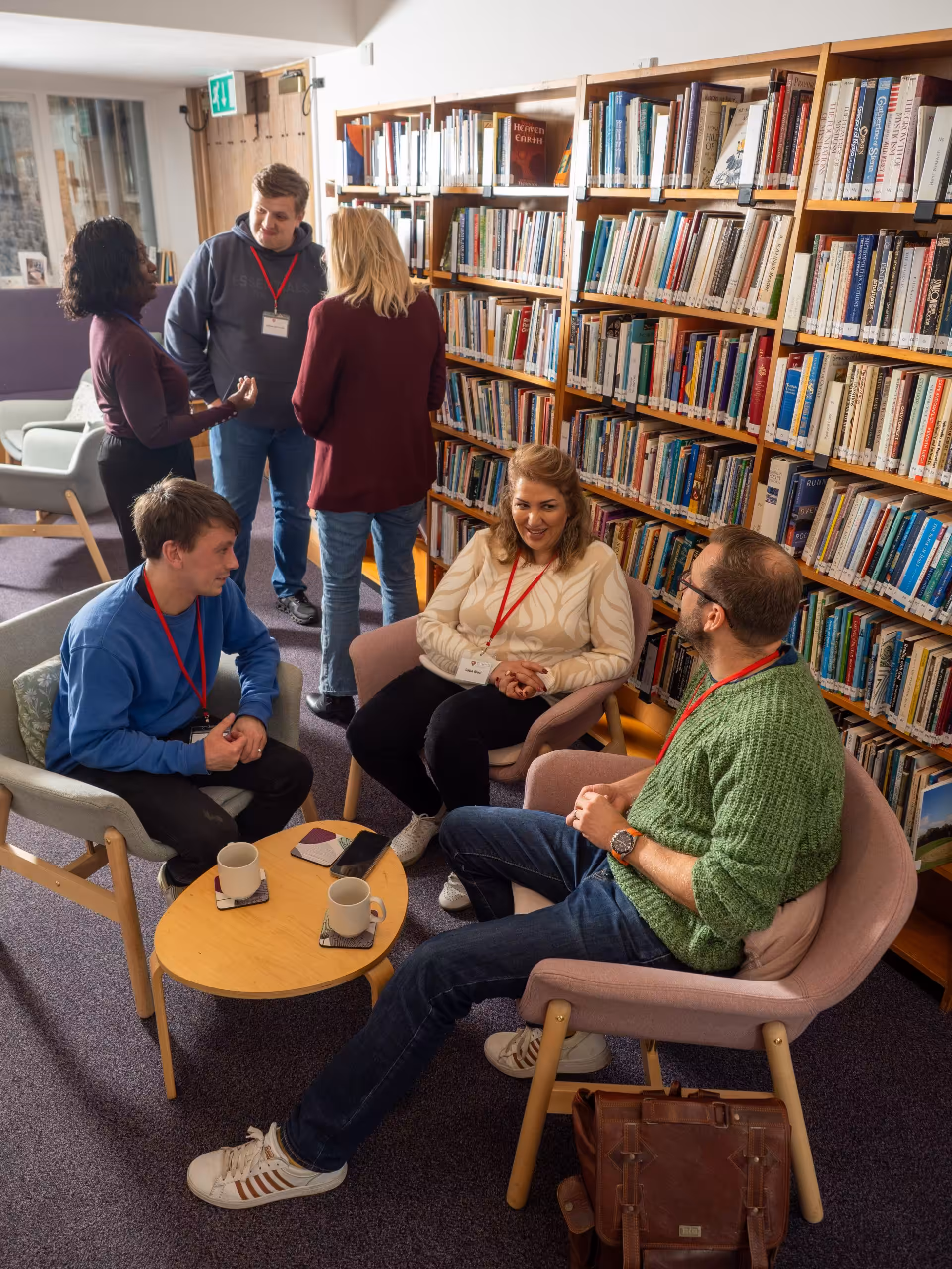 People sitting in comfortable chairs in a library, discussing things